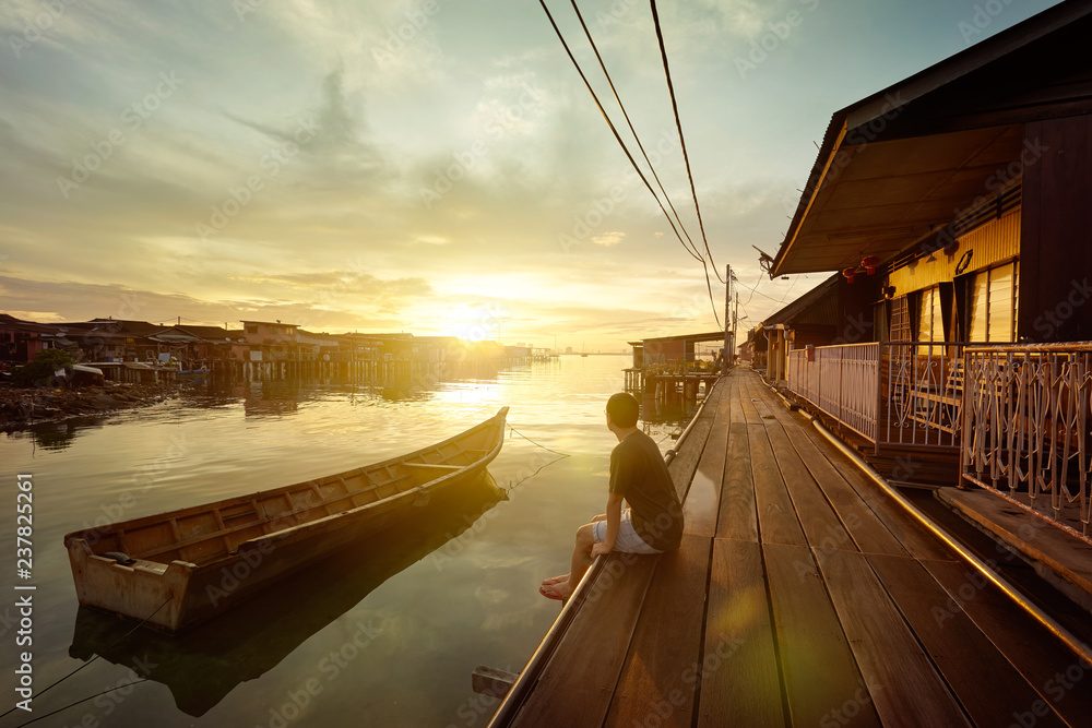 年轻人在马来西亚槟城的码头上观看日出。