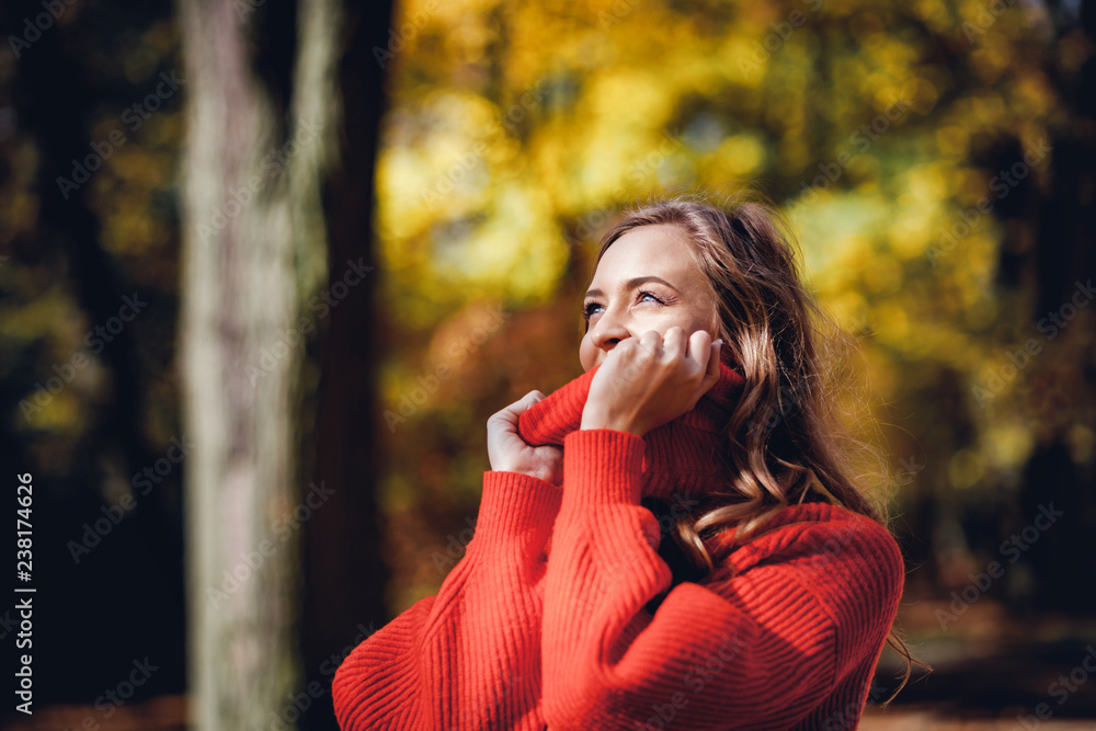 穿着柔软保暖针织毛衣的自然年轻女性在户外行走，秋天和春天