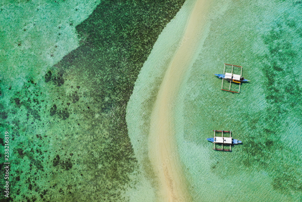 无人机鸟瞰停泊在El Nido群岛绿松石海岸水域和珊瑚礁的船只