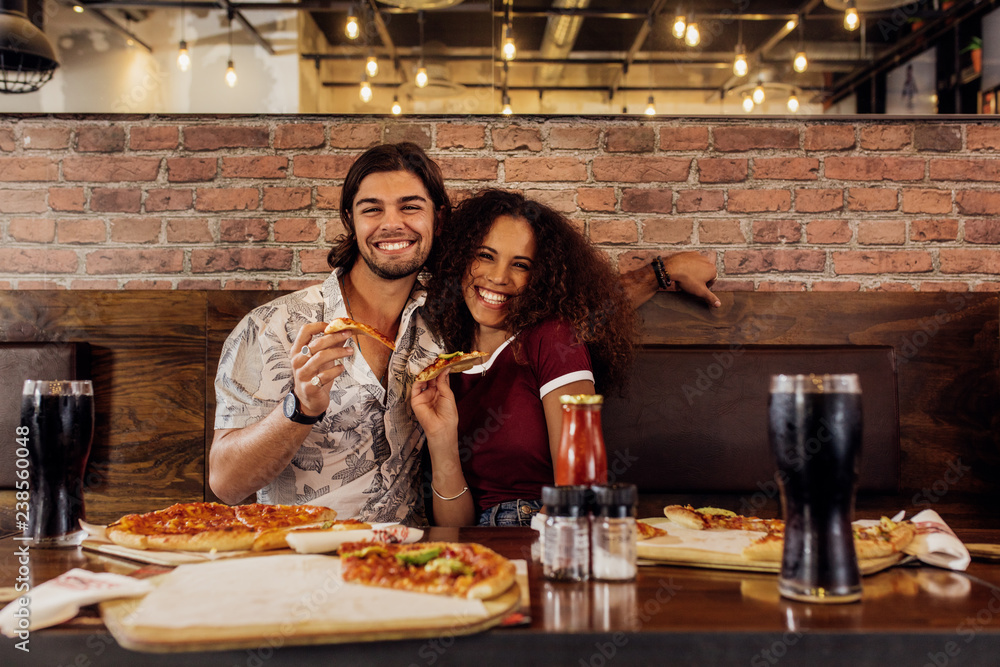 微笑的情侣在咖啡馆吃披萨