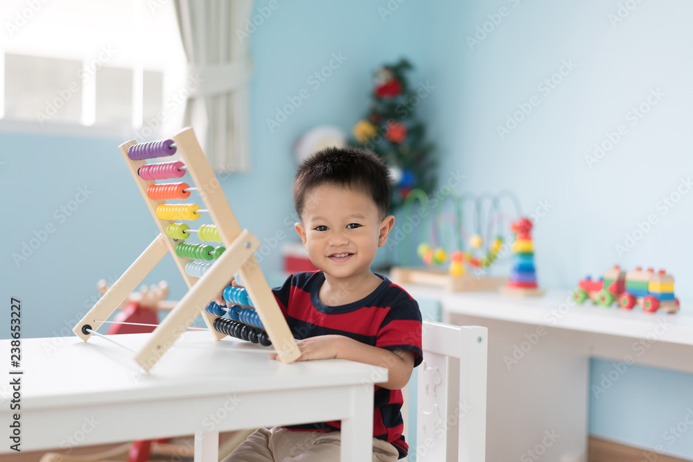 亚洲幼童学会数数。可爱的孩子在玩算盘玩具。小男孩玩得很开心
