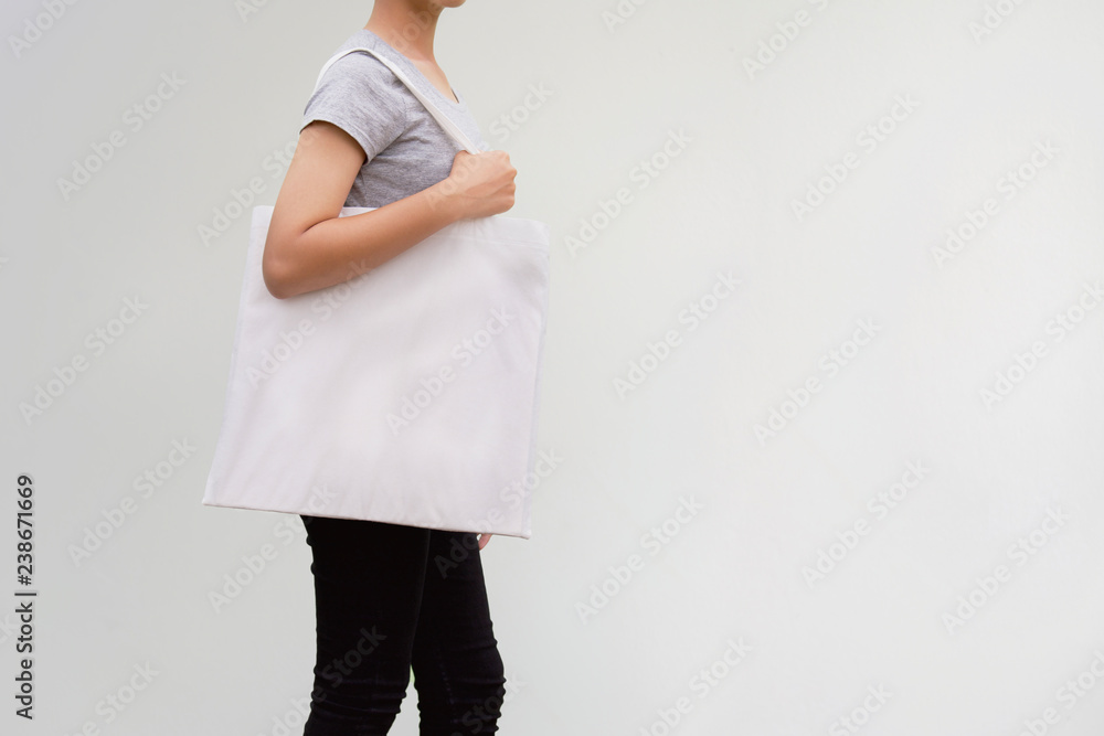 年轻女子在墙上拿着棉袋。环保理念