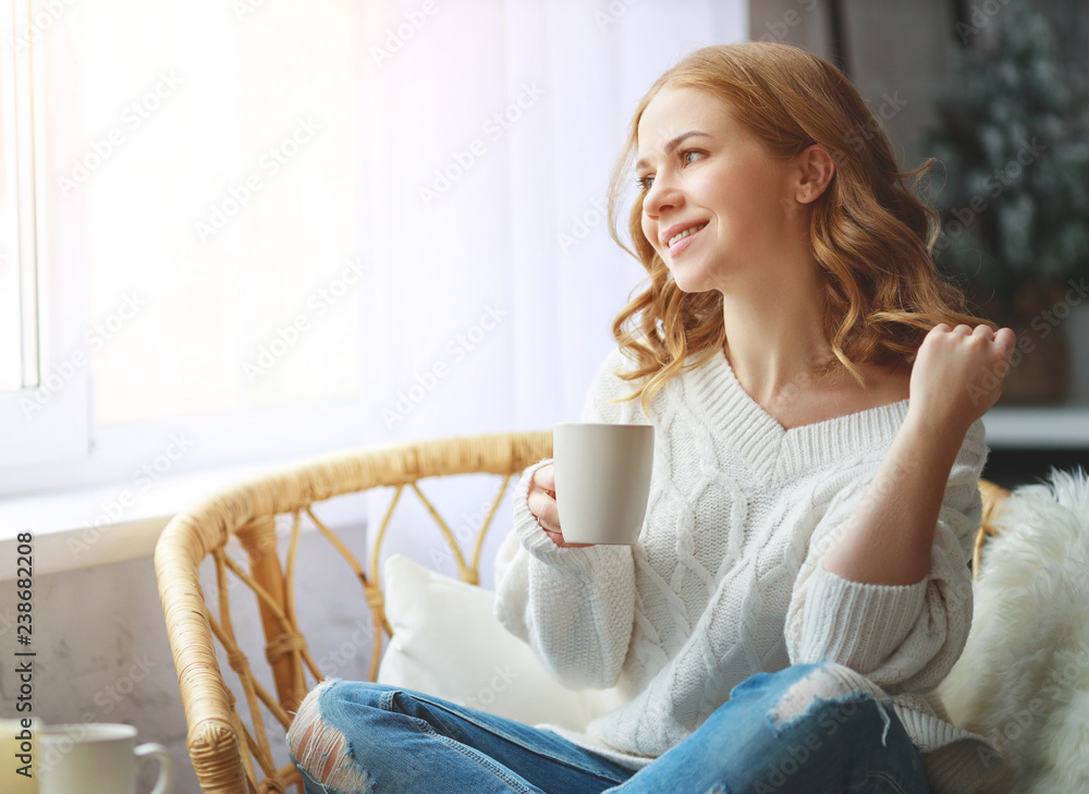 快乐的年轻女人在冬天靠窗喝早晨的咖啡