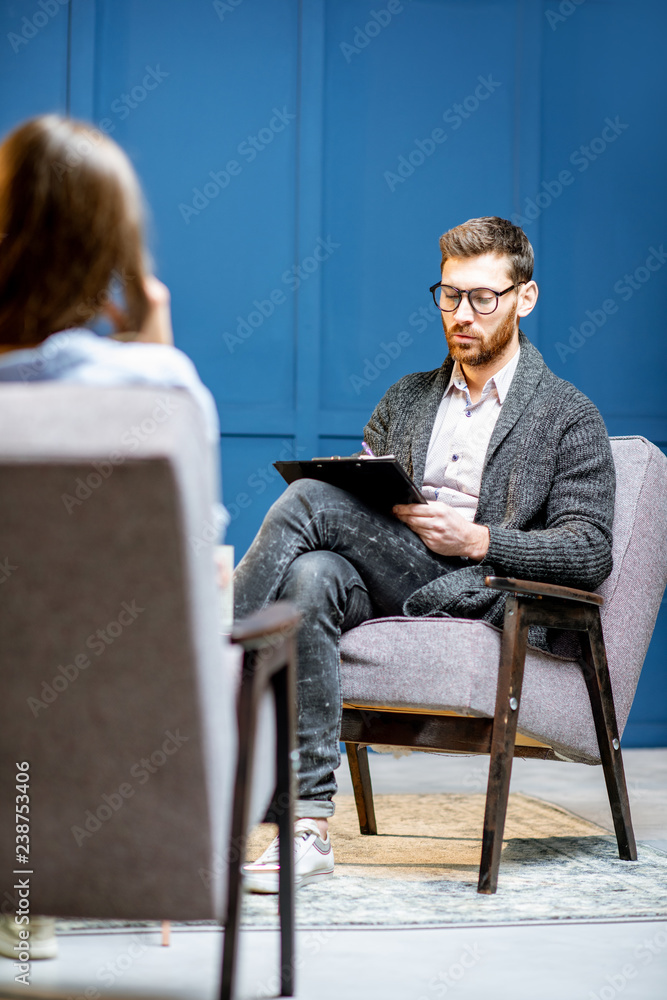 英俊的男性心理学家在听女性客户坐在心理会议上
