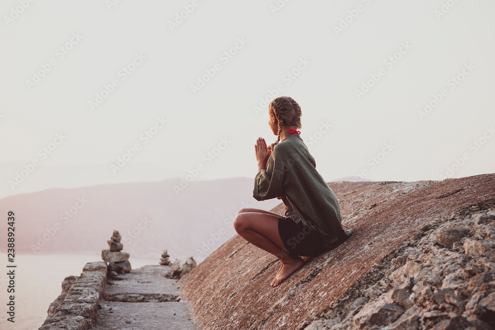 年轻的女游客坐在罗兹岛Monolithos城堡的古老石头上冥想，