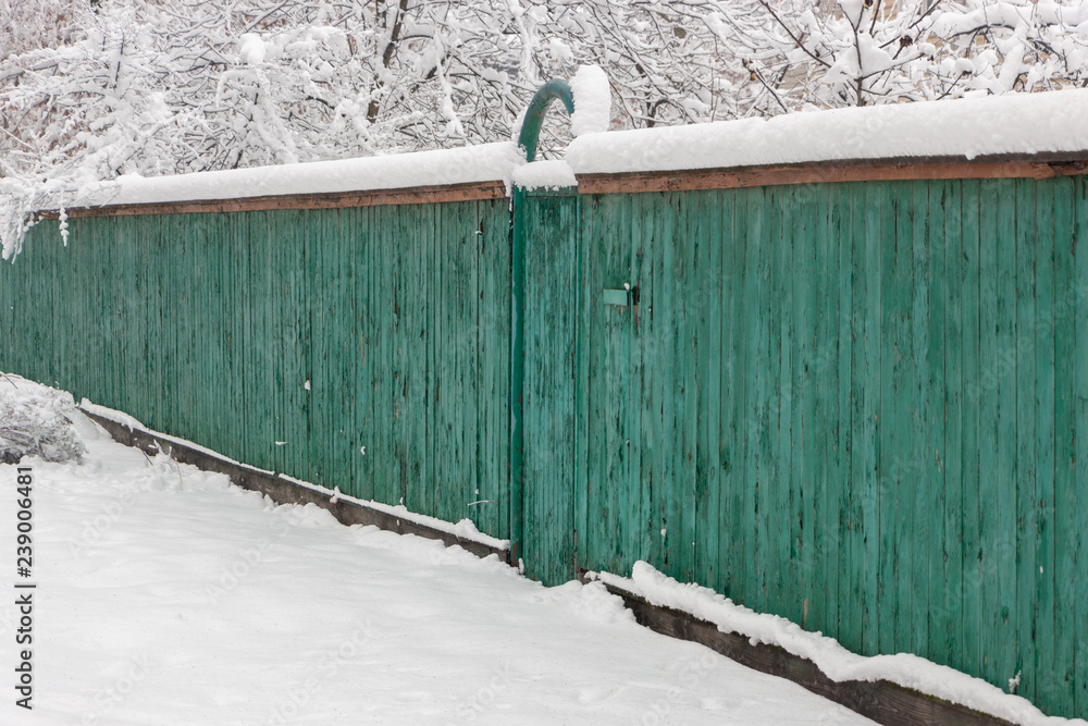 白雪覆盖的木板路古老的绿色围栏。乡村灰暗的冬日