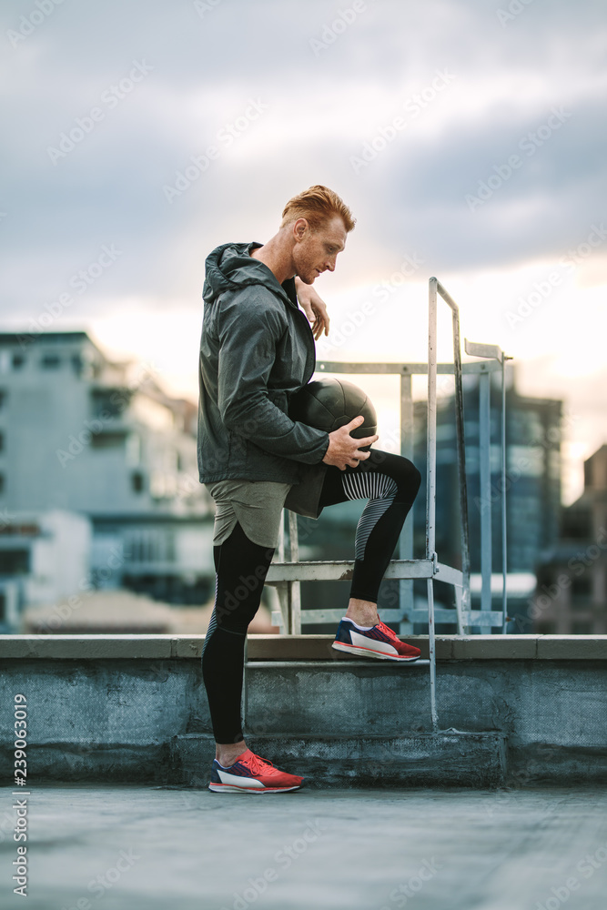 Athlete standing on rooftop staircase looking  down