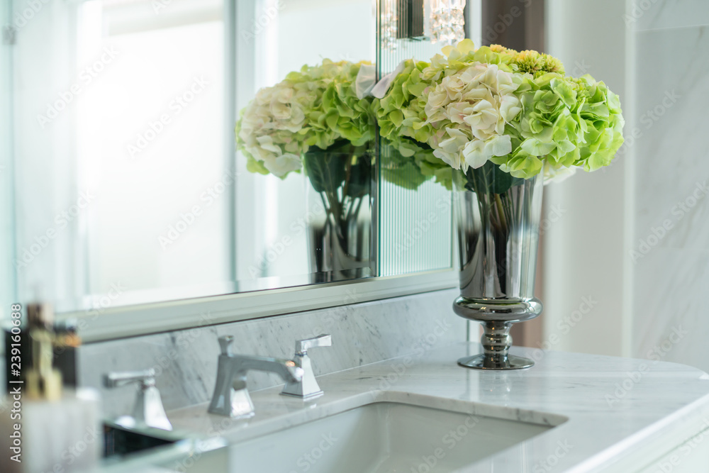 白色室内卫生间设计中洗手盆上装饰的白色和绿色花瓶
