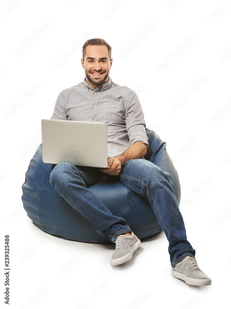 年轻人拿着笔记本电脑坐在白色背景下的豆袋椅上