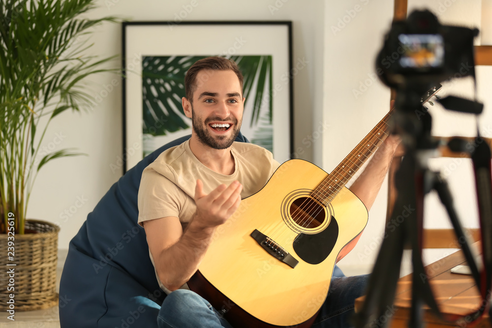 年轻人带着吉他在家录制视频