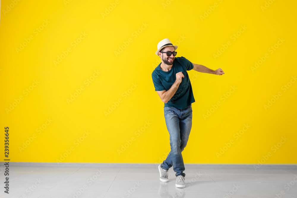 英俊的年轻人在彩色墙上跳舞