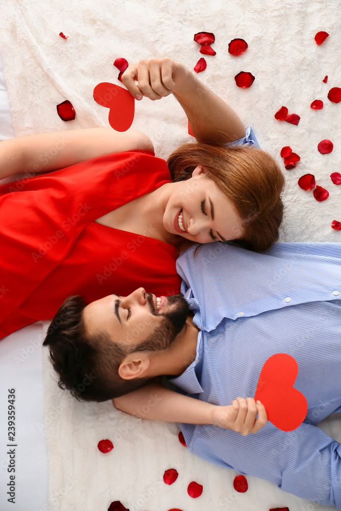 幸福的红心夫妇躺在家里的床上。庆祝圣瓦伦丁节