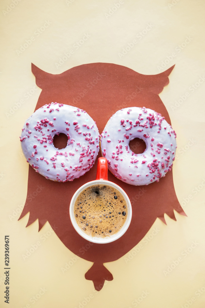 纸猫头鹰配美味的甜甜圈和一杯淡背景咖啡