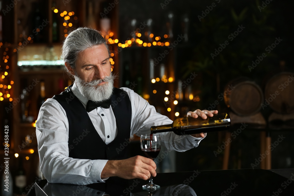 酒吧里的高级酒吧服务员把酒倒进杯子里