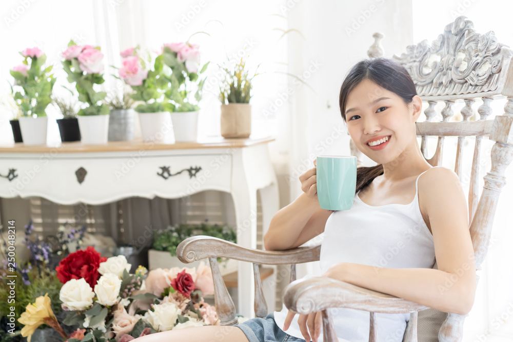 亚洲女人在家喝咖啡，在木椅上放松的肖像