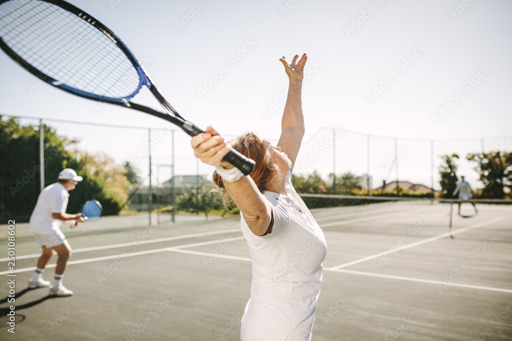 资深女子在打网球时发球