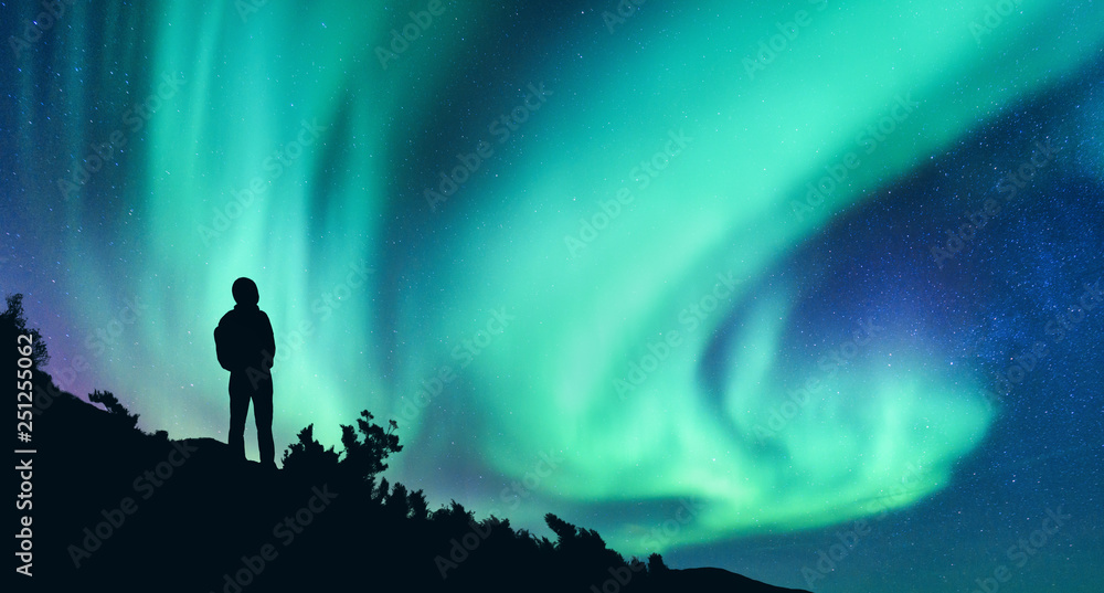 北极光和一个晚上背着背包的女人的剪影。山上的女孩，星空与