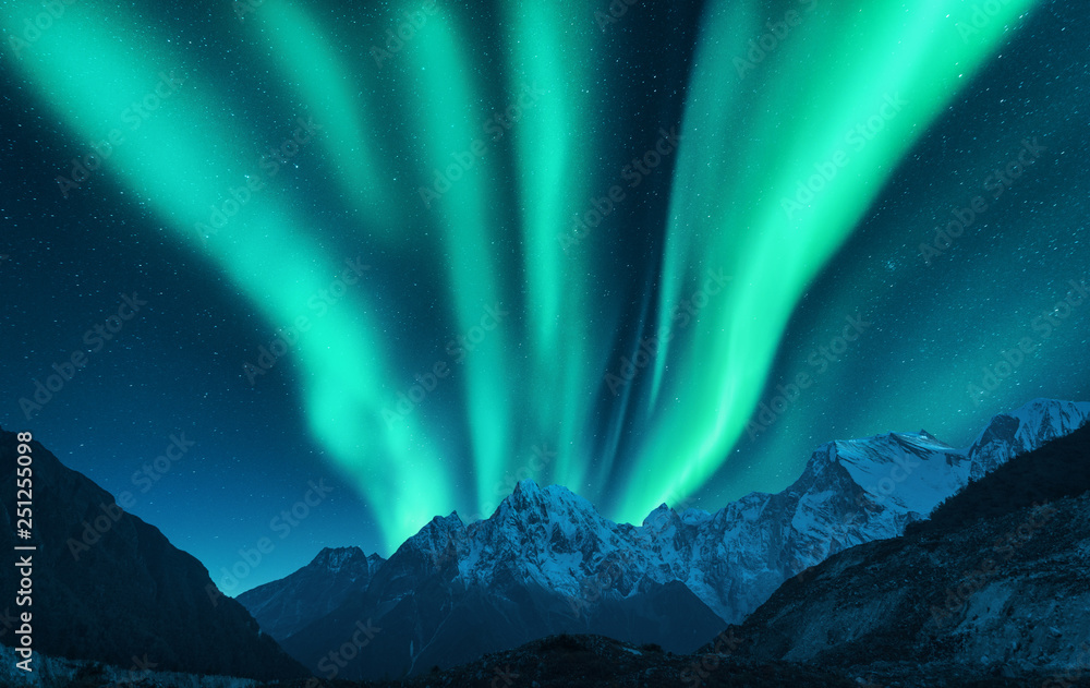 Aurora borealis above snow covered mountain range in europe. Northern lights in winter. Night landsc