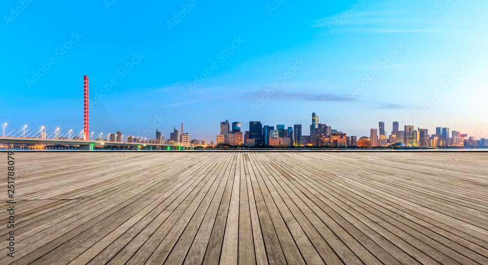 Empty wooden plank platform and Hangzhou city skyline at sunrise