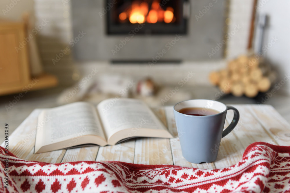 在燃烧的壁炉旁看书和喝茶。Hygge概念