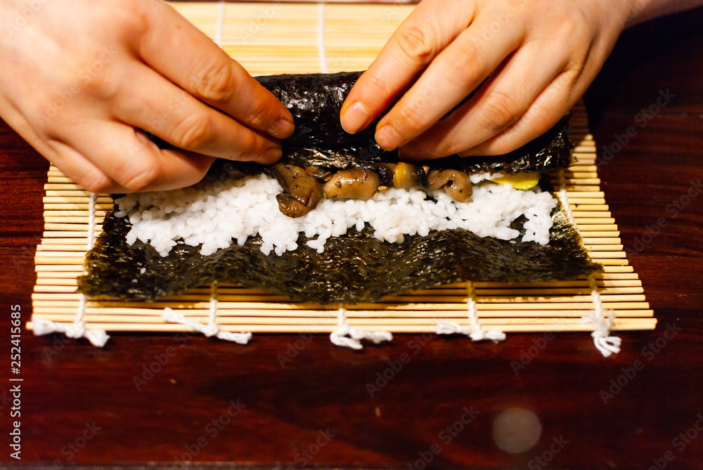 一个年轻女人在木桌上准备自制素食寿司