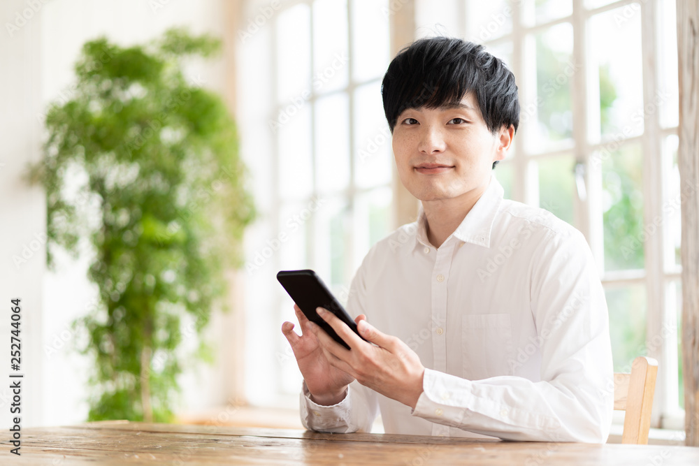 young asian man using smart phone in living room