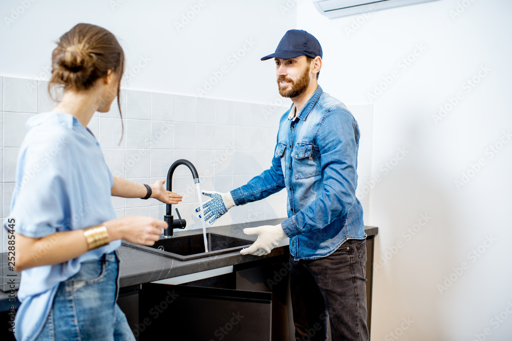 Handy man talking with young woman client after the repairment on the kitchen. Home repair service c