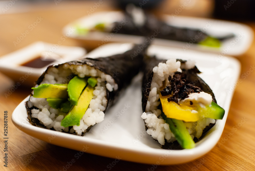 自制纯素食淡木寿司，在木桌上的一个小盘子里放上鳄梨和酱油。