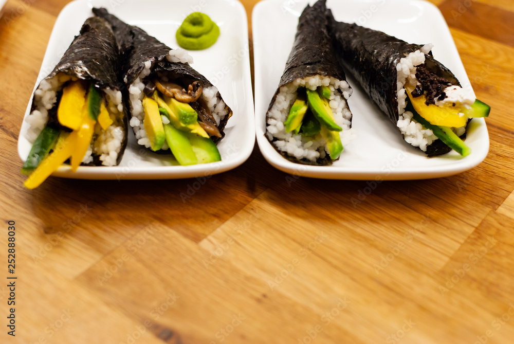 自制纯素食淡木寿司，在木桌上的一个小盘子里放上鳄梨和酱油。