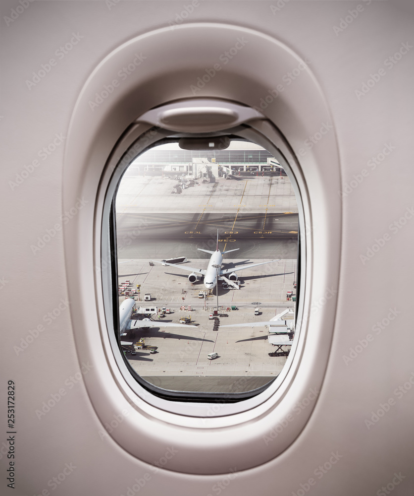 Airplane window view to terminal with airplanes