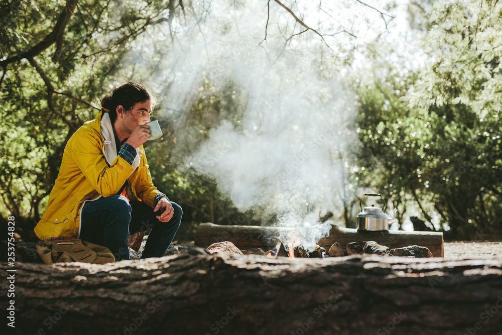 一名男子坐在篝火旁的森林里露营