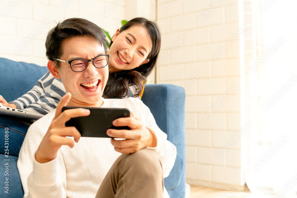幸福的亚洲甜蜜情侣一起在智能手机上玩游戏客厅家庭背景