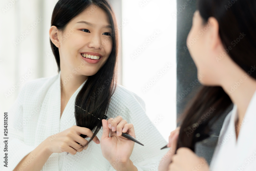 美丽的亚洲女人沐浴服刷头发，用镜子打扮浴室背景