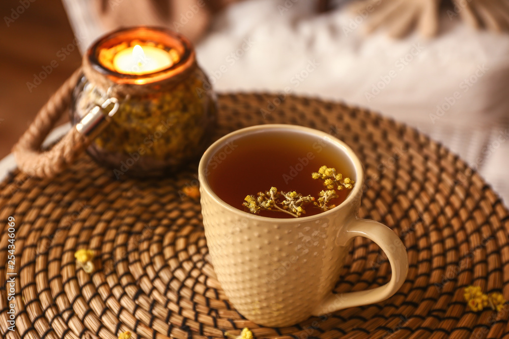 一杯热茶和柳条垫上的蜡烛支架
