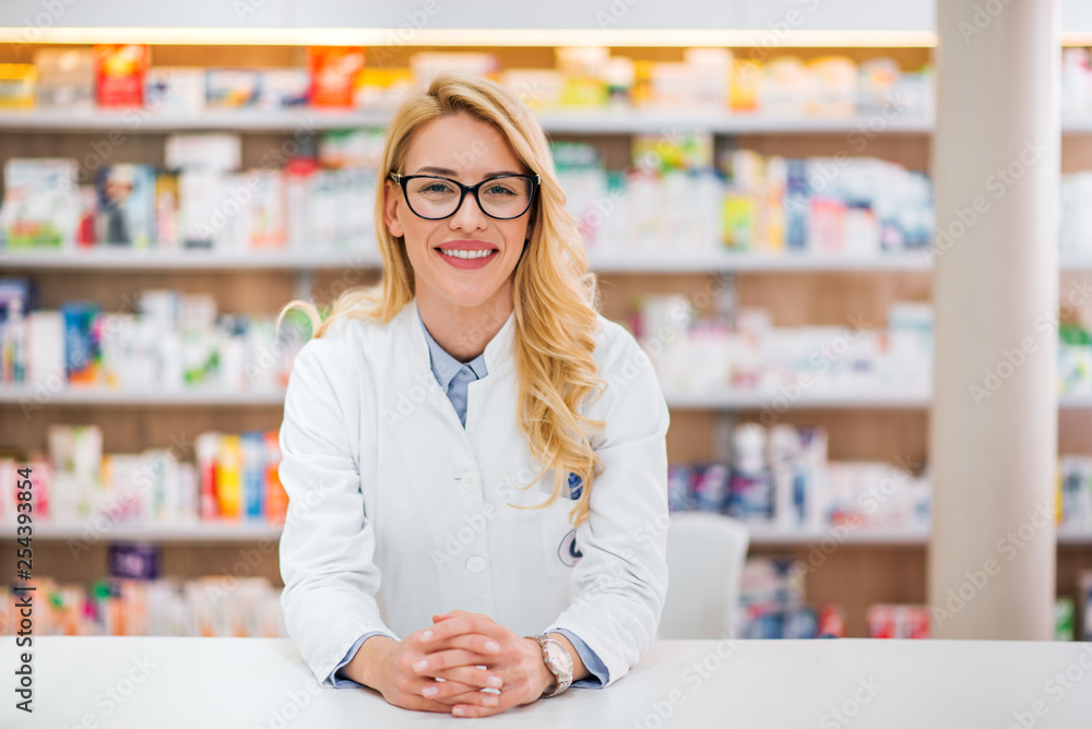一位美丽的金发药剂师靠在药店柜台上的肖像。