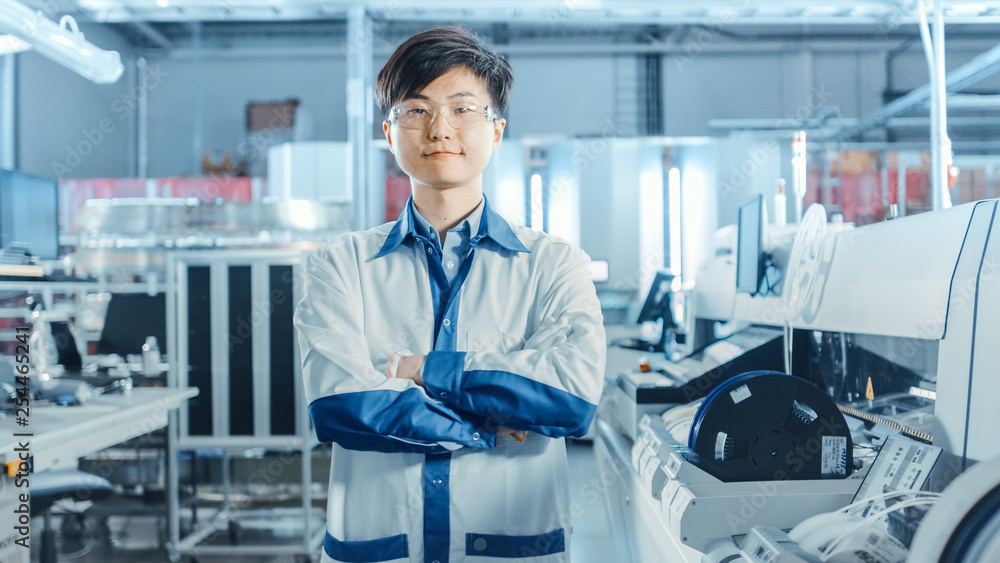 高科技工厂：交叉双臂的亚洲工人肖像。背景电子印刷