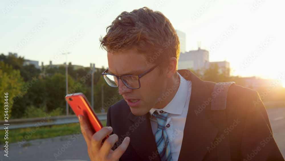 CLOSE UP: Irritated yuppie gets bad news and starts yelling at his mobile phone.
