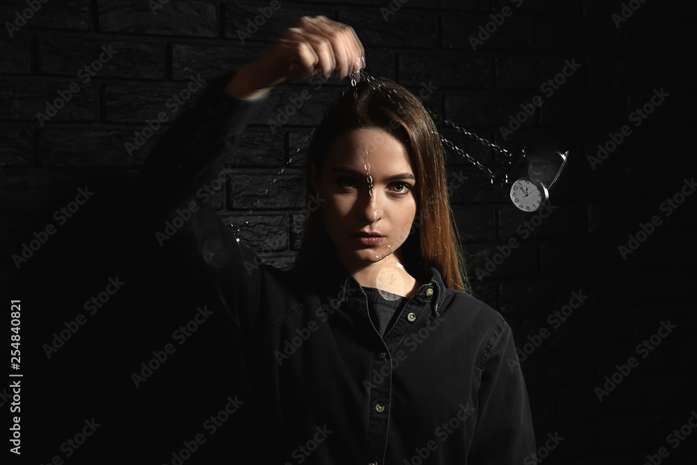 Female hypnotist with swinging pendulum on dark background