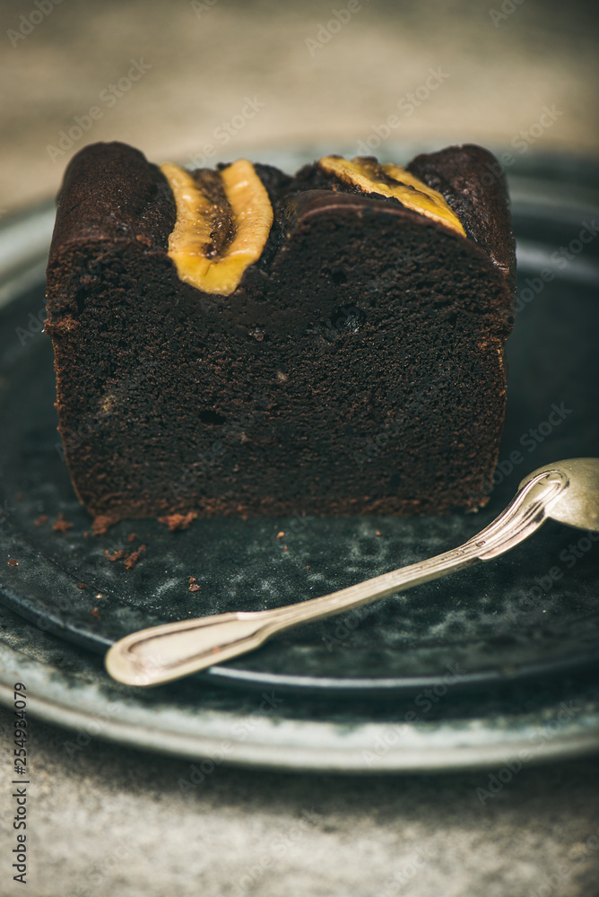 一块新鲜出炉的黑巧克力香蕉面包蛋糕甜点，放在灰色混凝土桌子上