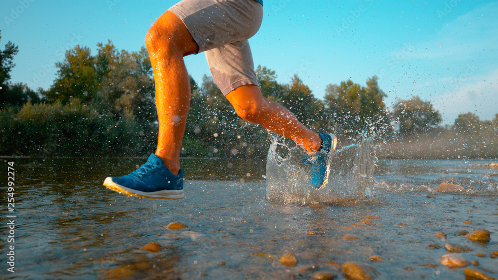 低角度：阳光明媚的早晨，一个年轻人在河边奔跑的电影镜头。