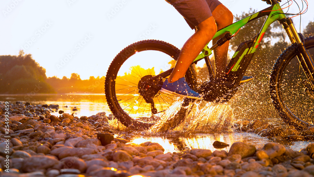 太阳耀斑：在浅水中骑山地自行车的不知名运动员。