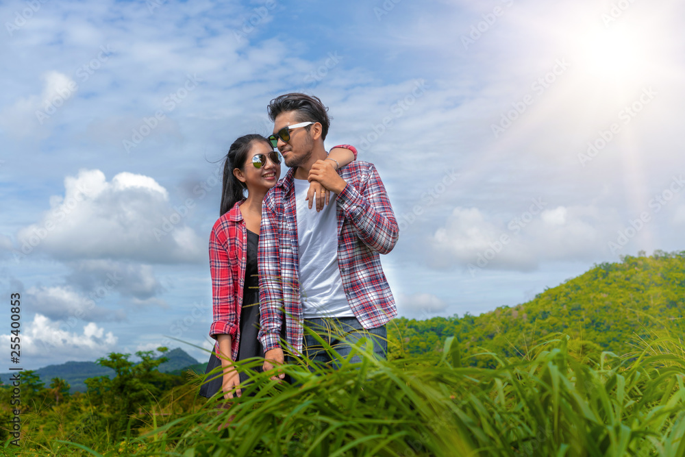 幸福的一对情侣在山上的绿草地里浪漫漫步。旅行和蜜月概念。