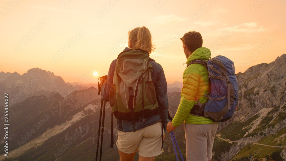 特写：一对不知名的徒步旅行者夫妇在山顶观看日落。
