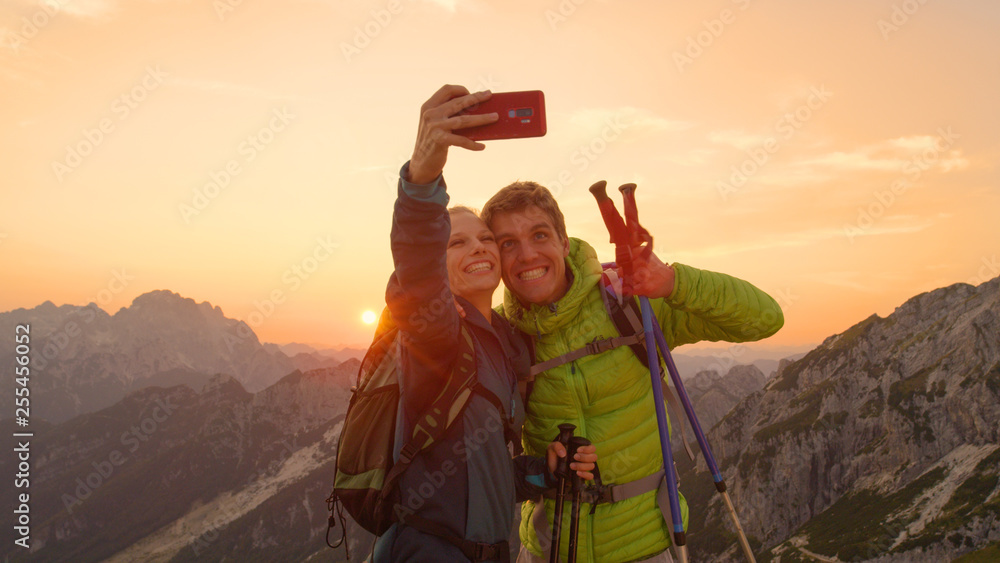 特写：可爱的徒步旅行者夫妇在日落时分在令人惊叹的阿尔卑斯山自拍。
