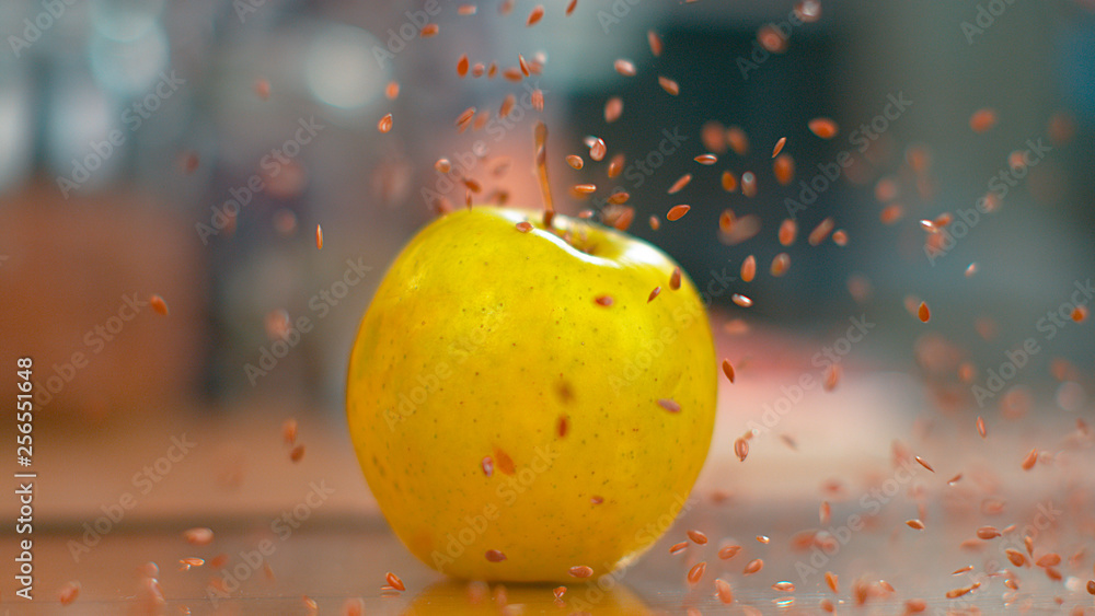 MACRO，DOF：微小的棕色亚麻籽从空中掉落到黄色的苹果上。