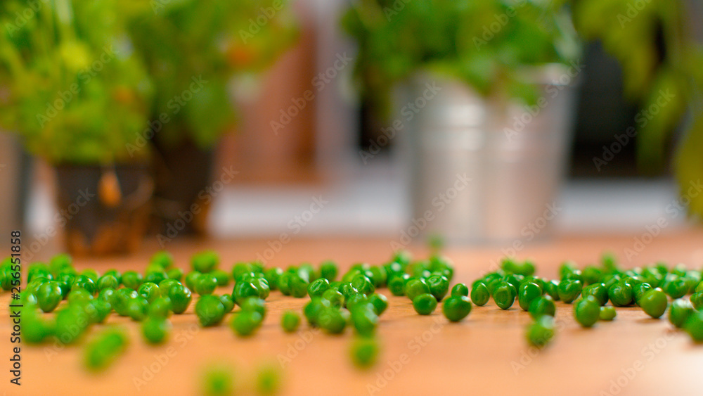 MACRO，DOF：美味的绿豌豆在厨房的木制柜台上滚动和弹跳。