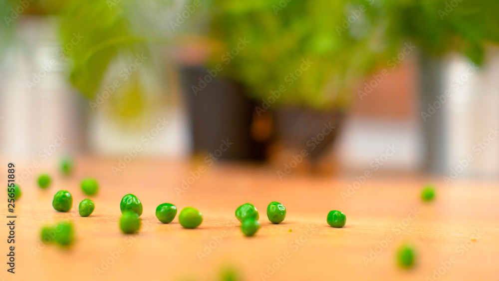 MACRO：闪亮的熟豌豆散落在木制台面周围。