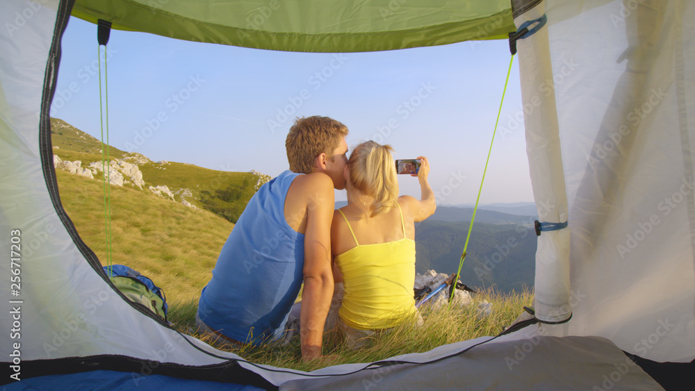 特写：快乐的旅游情侣坐在帐篷前自拍