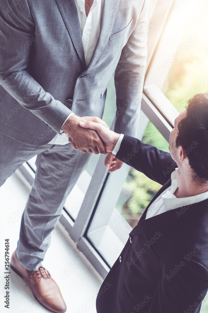 在现代职场办公室，商人与另一位商业伙伴握手。人们是企业