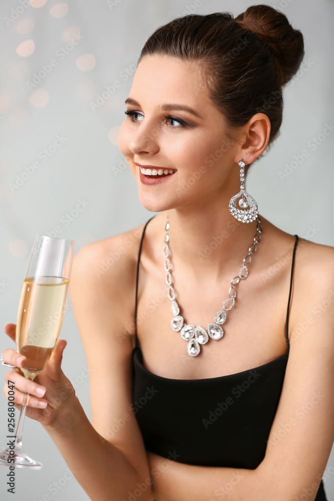 年轻女子，戴着漂亮的珠宝，背景是一杯香槟